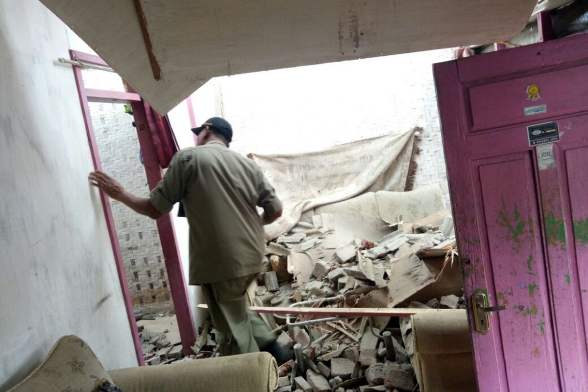 Seorang petugas sedang mengecek salah satu rumah yang rusak akibat gempa Banten, Selasa (23/1/2018).