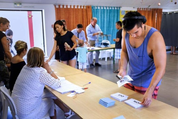 Seorang pria mengambil surat suara untuk memberikan suara dalam referendum kemerdekaan New Caledonia dari Perancis, Minggu (4/11/2018). (AFP/Theo Rouby)a