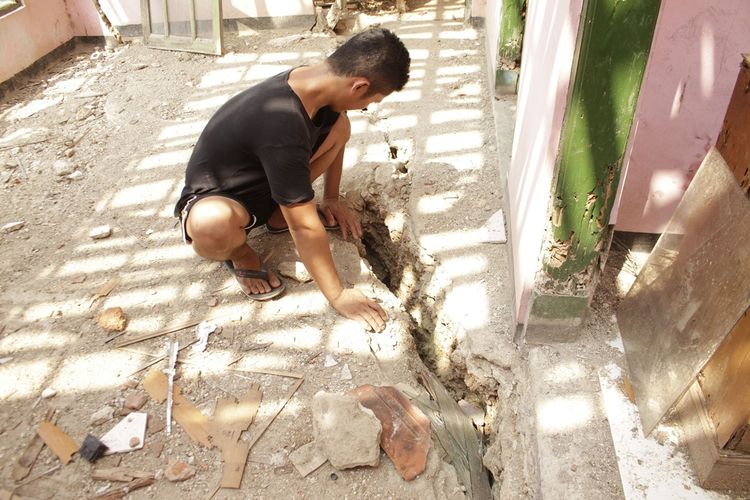 Seorang warga menunjukkan retakan pada lantai bangunan rumah yang terancam ambruk di Kampung Babakansirna, Desa Limusnunggal, Kecamatan Bantargadung, Sukabumi, Jawa Barat, Kamis (28/11/2019),