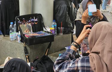 Penonton memanfaatkan jasa eye makeup yang ditawarkan di lokasi konser Suga |Agust D Tour in Jakarta Day 2, ICE BSD, Tangerang, Banten, Sabtu (27/5/2023).