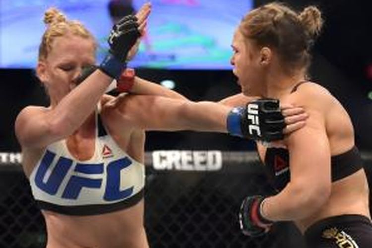 Petarung UFC asal Amerika Serikat, Ronda Rousy (kanan), melancarkan pukulan kepada sesama petarung AS, Holly Holm, pada pertarungan kelas bantam di Mebourne, Australia, Minggu (15/11/2015).
