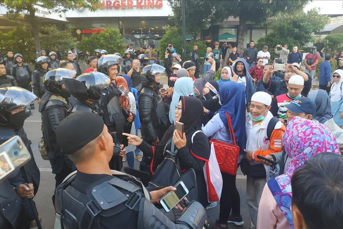 Jemaah di Perempatan Sarinah, Jamarta Pusat yang sebelumnya mendirikan salat gaib bersalaman dengan anggota Brimob yang berjaga di depan gedung Djakarta Theatre, Jumat (24/5/2019) sore.