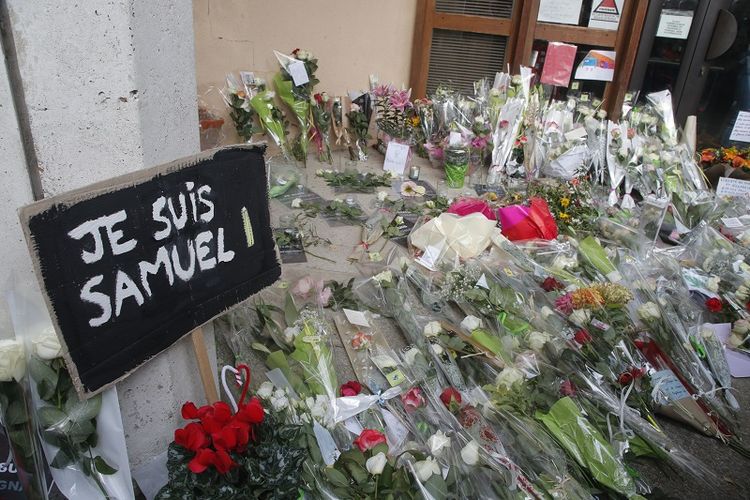 Sebuah poster bertuliskan Saya Samuel dan bunga-bunga tergeletak di luar sekolah tempat guru sejarah yang terbunuh, Samuel Paty, bekerja, Sabtu, 17 Oktober 2020 di Conflans-Sainte-Honorine, barat laut Paris. 