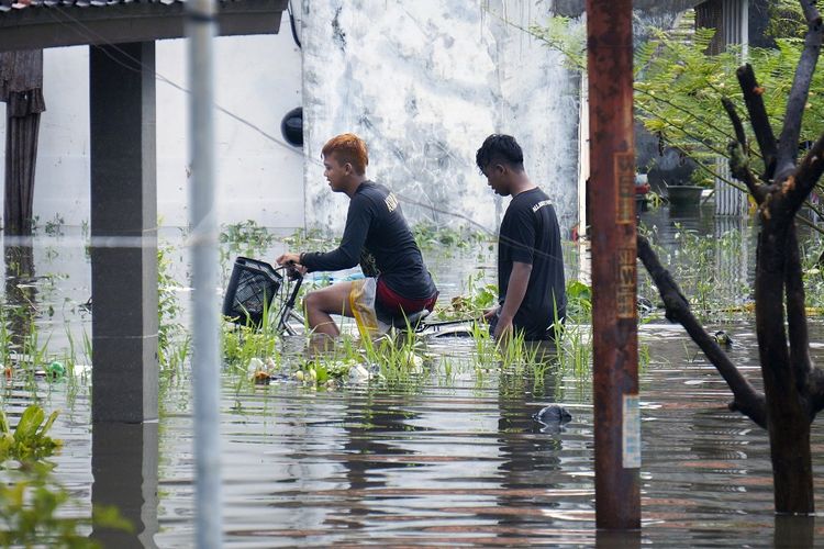 Warga melewati jalan desa yang terendam banjir di Tirto, Pekalongan, Jawa Tengah, Senin (24/2/2020). Berdasarkan data Badan Penanggulangan Bencana Daerah (BPBD) Kota Pekalongan, sebanyak sekitar 80 persen wilayah Kota Pekalongan terdampak banjir akibat hujan sejak Minggu (23/2) sore dengan ketinggian air rata-rata mencapai 30-100 cm. ANTARA FOTO/Harviyan Perdana Putra/aww.