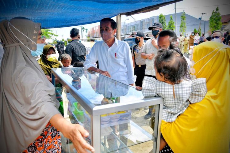 Presiden Joko Widodo menghampiri Juhari, pedagang kaki lima yang membentangkan spanduk saat kunkernya di Sorong, Papua Barat, Senin (04/10/2021).