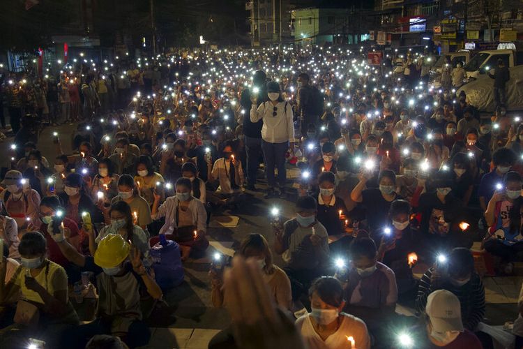 Pengunjuk rasa anti-kudeta menyalakan lampu ponsel mereka selama unjuk rasa malam yang diterangi cahaya lilin di Yangon, Myanmar Minggu (14/3/2021).