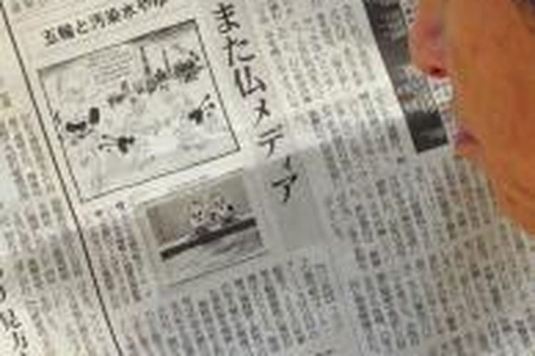 Seorang warga Jepang tengah membaca harian lokal yang memuat kartun di media Perancis, Kamis (12/9/2013). Kartun itu mempersoalkan pemilihan Jepang sebagai tuan rumah Olimpiade 2020 dengan menampilkan kartun satire berlatar PLTN Fukushima yang mengalami kebocoran radioaktif setelah dihajar gempa dan tsunami pada 2011.