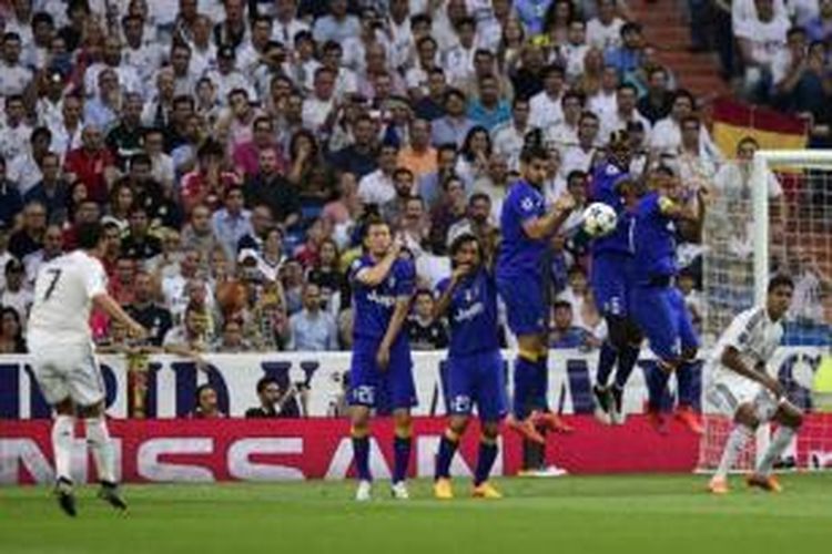 Striker Real Madrid, Cristiano Ronaldo (kiri), melepaskan tendangan bebas yang nyari berbuah gol ke gawang Juventus pada laga leg kedua semifinal Liga Champions di Stadion Santiago Bernabeu, Madrid, Rabu (13/5/2015).