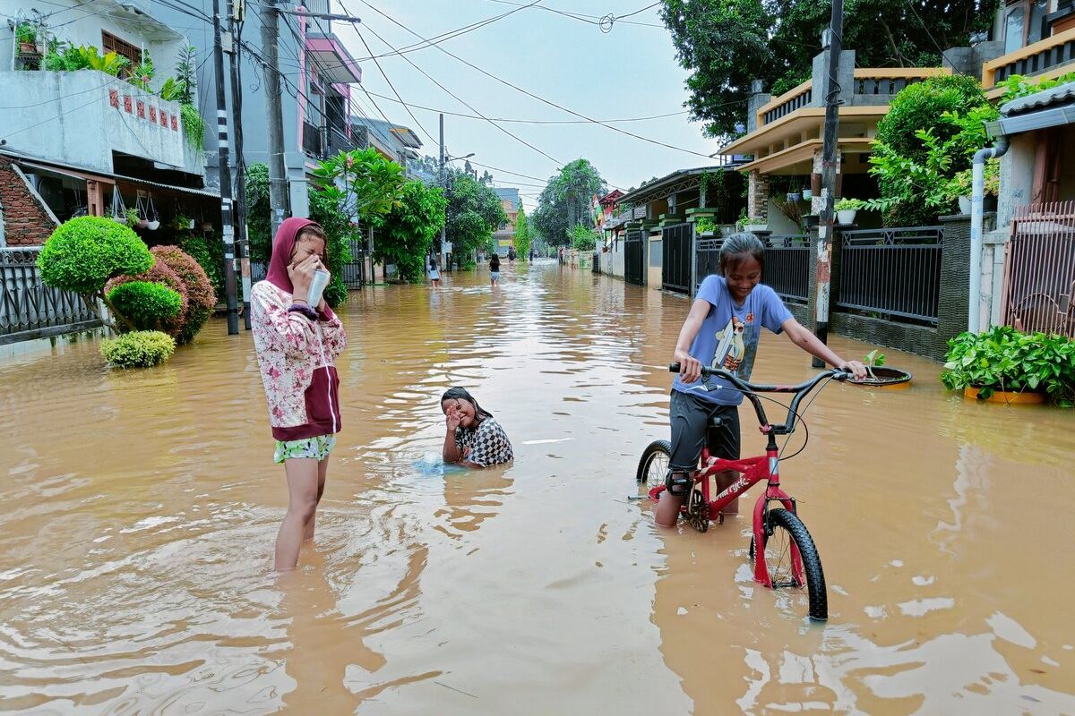 Anak-anak yang sedang asyik bermain meskipun daerah tempat tinggal mereka dilanda banjir, Minggu (11/9/2022).