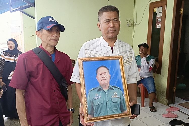 Kaka dari korban, Oyib Gunawan (58) saat memperlihatkan foto almarhum Mayor (cpl) Anda Rohana salah satu korban meninggal akibat ledakan amunisi tak terpakai di Kabupaten Garut, Senin kemarin. Rencananya jrnazah akan dimakamkan di kampung halamannya di Kecamatan Cileunyi, Kabupaten Bandung, Jawa Barat, Selasa (13/5/2025)