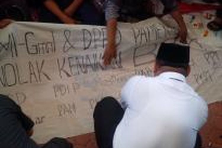 Anggota DPRD Pamekasan, mendantangani spanduk berisi penolakan kenaikan BBM bersama GMNI dan HMI Pamekasan, Senin (10/11/2014). 
