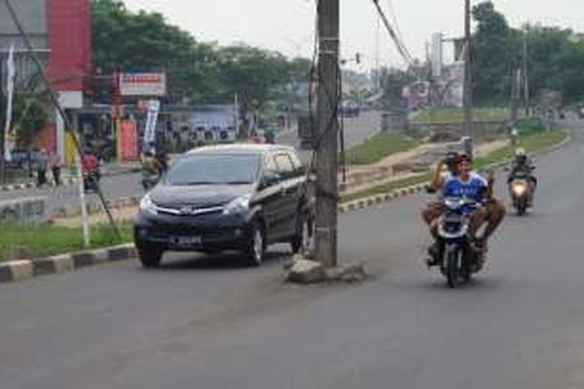 Sebanyak empat tiang listrik berdiri di tengah Jalan Raya Ciater, Tangerang Selatan, Selasa (31/5/2016). Keberadaan tiang listrik di tengah jalan ini kerap membuat pengendara terlibat kecelakaan di daerah tersebut. 