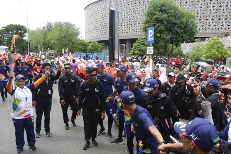 Atlet Anggar Aceh Erma (kiri) membawa obor Asian Games 2018 melintas di depan Museum Tsunami, Banda Aceh, Besar, Aceh, Selasa (31/7/2018). Api obor Asian Games 2018 diarak keliling kota Banda Aceh sebelum dibawa menuju ke kota Medan, Sumatera Utara dan kota lainnya di Pulau Sumatera.