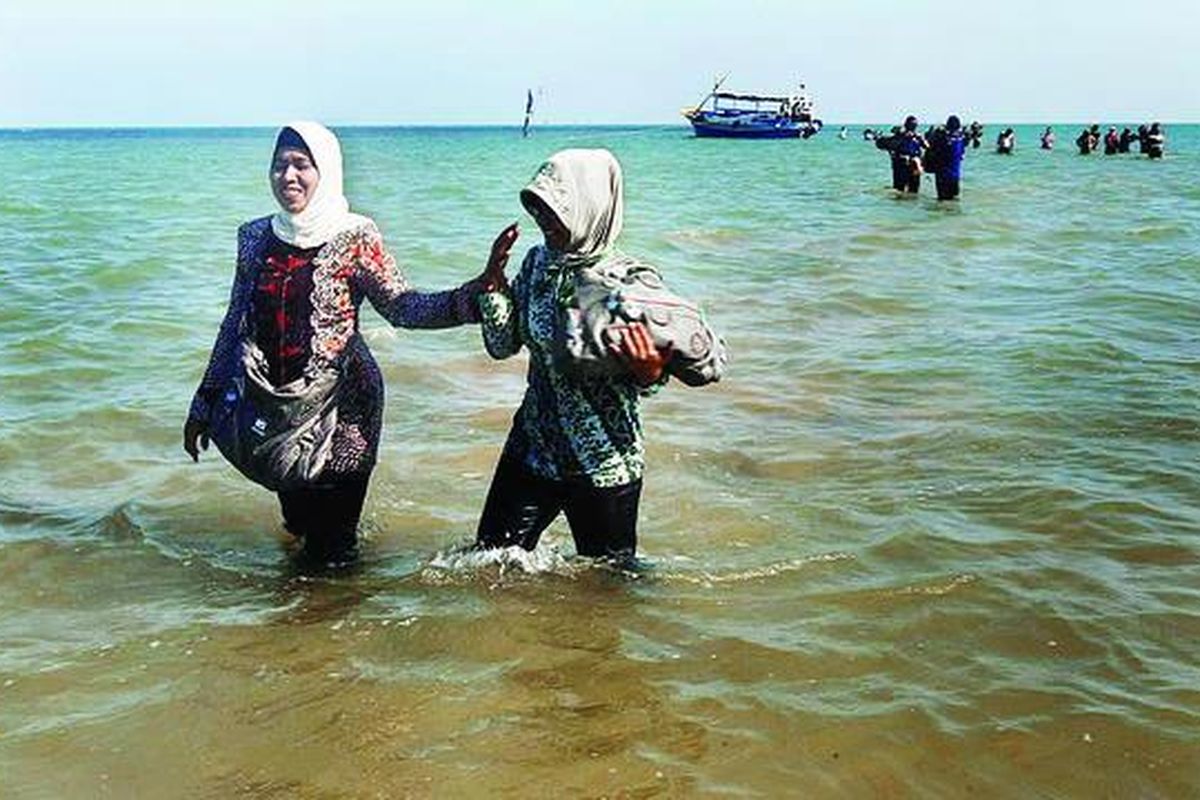 Penumpang dari Pulau Mandangin melintasi kawasan Pantai Camplong, Sampang, Jawa Timur, setelah turun dari perahu penyeberangan menuju daratan, Jumat (10/8). Perahu penyeberangan Pulau Mandangin-Sampang terpaksa berlabuh di pantai tersebut. Hal itu  karena tidak ada tempat terdekat bagi perahu penyeberangan berlabuh setiap air laut surut dan tidak bisa masuk ke muara Sungai Ajer. Para penumpang terpaksa turun di Pantai Camplong yang bibir pantainya berjarak sekitar 500 meter dari perahu berlabuh. Hingga kini belum ada dermaga yang menunjang penyeberangan tersebut.