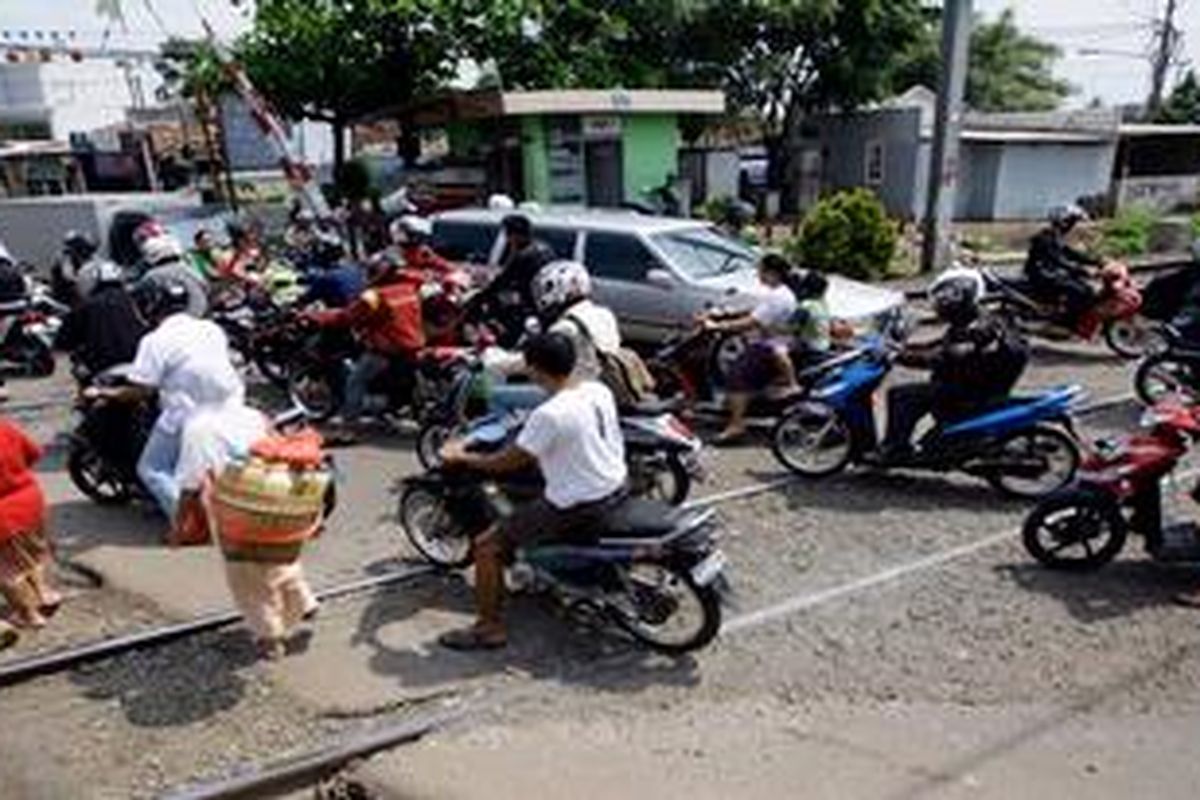 Pengguna jalan melintas di perlintasan kereta api di sekitar Pasar Bintaro, Pesanggrahan, Jakarta Selatan, Kamis (4/4/2013). Pertemuan lalu lintas dari empat arah di  pintu perlintasan itu menjadi penyebab kemacetan. Kondisi ini tentunya menyebabkan kawasan itu rawan kecelakaan yang melibatkan kereta api.
 
