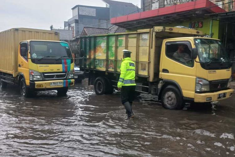 Sejumlah petugas kepolisian tengah melakukan penertiba arus lalu lintas di Kecamatan Dayeuhkolot, Kabupaten Bandung, Jawa Barat, yang tersendat akibat banjir, Selasa (25/2/2025)