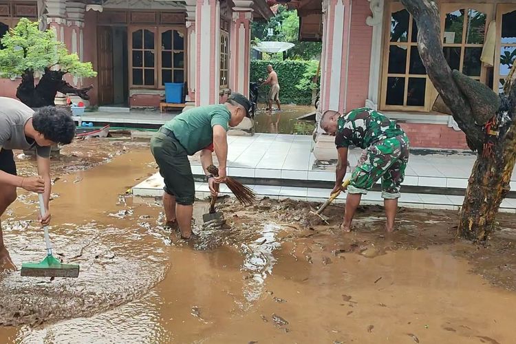 Warga dibantu aparat TNI membersihkan lumpur material banjir di Desa Kalibukbuk, Kecamatan Buleleng, Kabupaten Buleleng, Provinsi Bali, Kamis (9/2/2023).