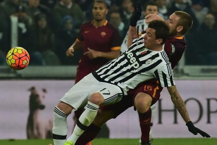 Striker Juventus, Mario Mandzukic, berebut bola dengan gelandang AS Roma, Daniele De Rossi, saat kedua tim bertanding pada lanjutan Serie A di Juventus Stadium, Minggu (24/1/2016).