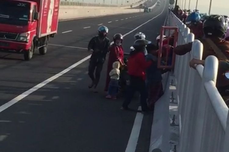 Pengendara roda di bentang Jemabatan Suramadu saat saling bantu menurunkan kenddaarnnya setelah berhasil membuka pintu pagar pembatas jalur motor dan mobil. Kamis, (10/6/2021