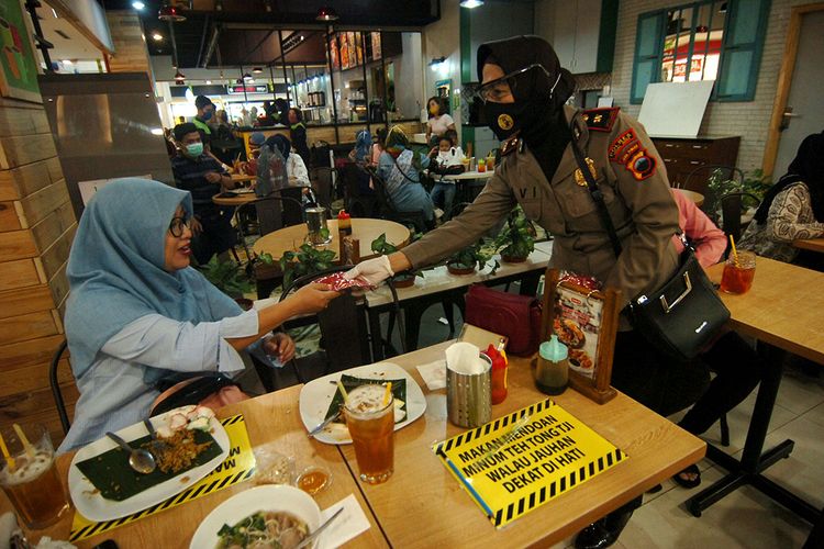 Petugas kepolisian membagikan masker kepada pengunjung restoran saat persiapan penerapan normal baru di salah satu mal, Tegal, Jawa Tengah, Kamis (28/5/2020). Kegiatan tersebut guna mengetahui kesiapan penerapan normal baru sekaligus mengantisipasi lonjakan penyebaran kasus COVID-19.