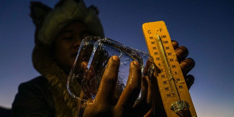 Petugas mengukur suhu udara yang turun hingga minus tujuh derajat celcius, dan menyebabkan embun beku menyelimuti kompleks Candi Arjuna, di dataran tinggi Dieng, Banjarnegara, Jawa Tengah, Selasa (25/6/2019). Embun beku yang muncul akibat penurunan suhu ekstrem hingga di bawah nol derajat celcius, telah terjadi sebanyak sepuluh kali sejak pertengahan Mei, dan menjadi daya tarik bagi wisatawan. 