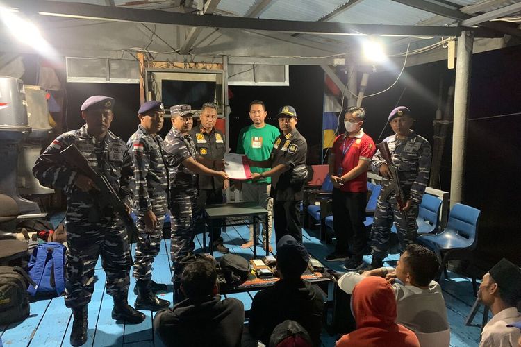 Petugas TNI AL saat menyerahkan 11 calon pekerja migran kepada pihak Imigrasi usai dicegat akan berangkat ke Malaysia di Kabupaten Kepulauan Meranti, Riau, Sabtu (6/8/2022).