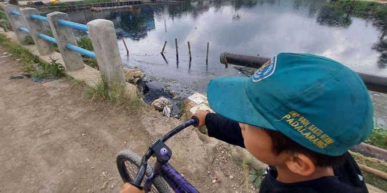 Warga beraktivitas di sekitar Situ Ciburuy, Kabupaten Bandung Barat yang berubah warna menjadi hitam pekat dan bau tak sedap setelah tercemar limbah, Kamis (14/7/2022).