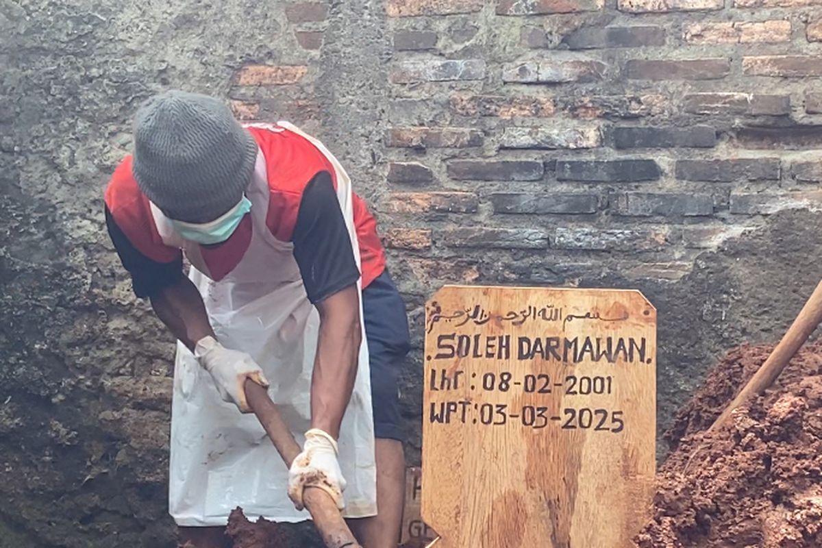 Seorang warga tengah menguburkan tanah di makam Soleh Darmawan usai proses ekshumasi.