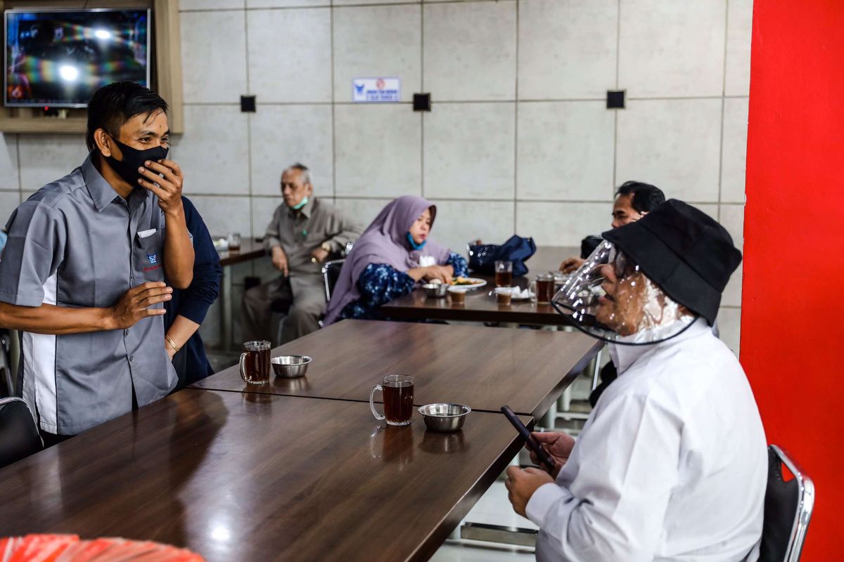 Pelayan menggunakan masker saat melayani pengunjung di Restoran Sederhana, Bendungan Hilir, Jakarta Pusat, Senin (8/6/2020). Sebagai bagian dari rencana penerapan kenormalan baru 8 Juni 2020, pemerintah DKI Jakarta mengharuskan pengusaha rumah makan membatasi kapasitas maksimal 50 persen, larangan penyajian makanan secara prasmanan dan tetap menerapkan protokol kesehatan.