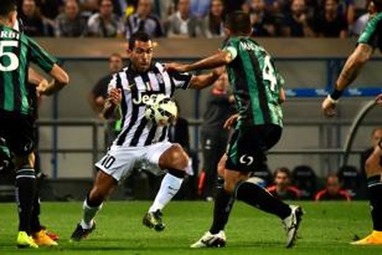 Striker Juventus, Carlos Teves, saat berebut bola dengan pemain Sassuolo pada lanjutan Serie-A di Stadion Citta del Tricolore, Sabtu (18/10/2014).