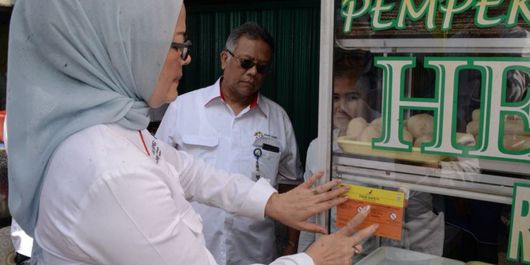 Kepala Badan Pengawasan Obat dan Makanan (BPOM) Penny Kusumastuti Lukito memasang stiker Pangan Aman saat edukasi keamanan pangan menjelang Asian Games 2018 di Palembang pada Rabu (11/7/2018).
