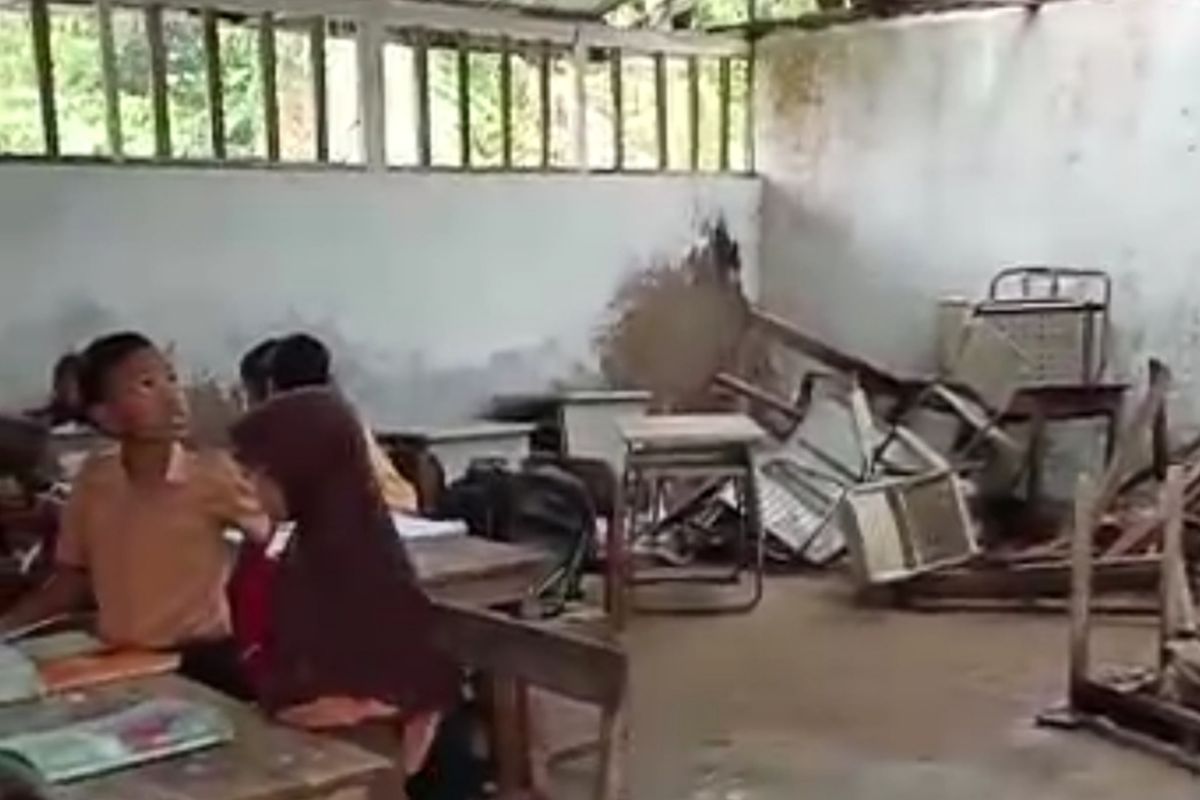 Proses belajar siswa SDN Sabuntan III di dalam ruang kelas yang atapnya mengalami kebocoran. 