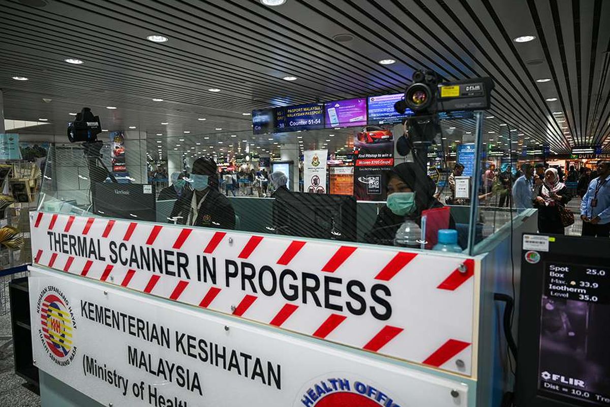 Malaysian health workers check the body temperatures of passengers by using a thermal scanner upon their arrival at the Kuala Lumpur International Airport in Sepang.