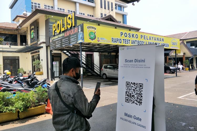 Seorang warga melakukan scan barcode melalui Aplikasi PeduliLindungi saat hendak memasuki Polsek Tanjung Priok, Jakarta Utara, Kamis (30/9/2021).