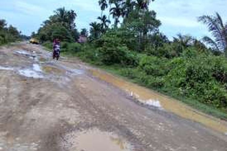 Warga melintas di jalan berkubang Desa Alue Bungkoh, Kecamatan Pirak Timu, Aceh Utara, Sabtu (28/5/2016)