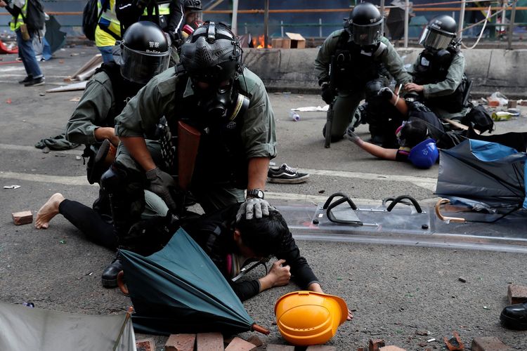 Polisi menahan seorang demonstran yang mencoba melarikan diri dari kampus di Polytechnic University Hong Kong dalam bentrokan yang terjadi pada 18 November 2019.