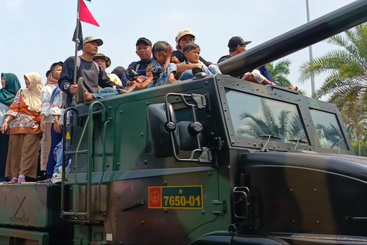 Sejumlah warga tampak menumpang kendaraan alat utama sistem senjata (alutsista) yang berjalan dalam parade alutsista untuk merayakan HUT ke-79 TNI, Sabtu (5/10/2024).