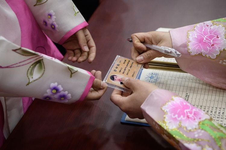Warga menggunakan kartu identitasnya untuk mendapatkan surat suara dalam pemilihan umum Korea Utara, Minggu (10/3/2018).