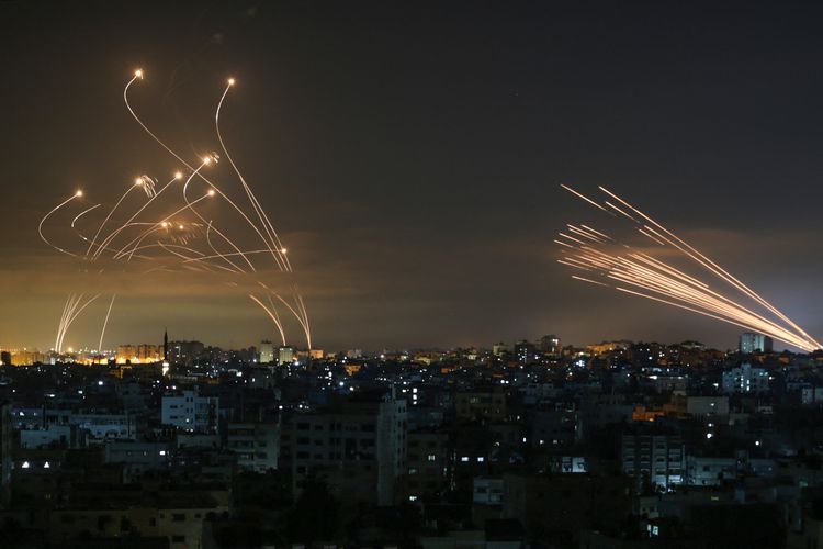 Sistem pertahanan rudal Iron Dome Israel (kiri) mencegat roket (kanan) yang ditembakkan oleh gerakan Hamas menuju Israel selatan dari Beit Lahia di Jalur Gaza utara seperti yang terlihat di langit di atas Jalur Gaza pada 14 Mei 2021. 