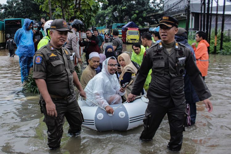 Masyarakat menumpang perahu karet milik Satpol PP Kramat Jati demi melewati Jalan Raya Pondok Gede, Kramat Jati, Jakarta Timur, Selasa (25/2/2020) yang terputus akibat banjir. Banjir di kawasan tersebut sudah terjadi pukul 04.00 WIB.