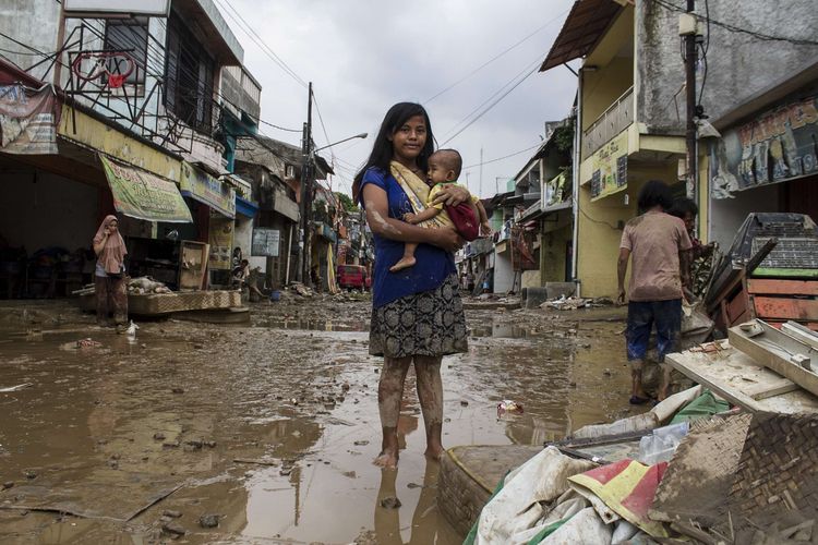 Sejumlah warga melintas di area pemukiman yang sempat terendam banjir di kawasan Pondok Gede Permai, Jati Asih, Bekasi, Jawa Barat, Kamis(2/1/2020). Banjir di kawasan tersebut, merupakan banjir terparah di wilayah Bekasi.