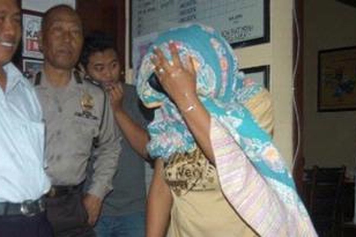 Istri otak pelaku pembunuhan Heru Herdiyanto, I Putu Anita Supra Dewi, juga diamankan polisi. Tampak Anita menutupi wajahnya. 