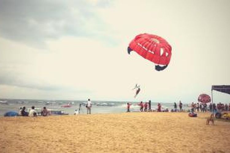 Wisatawan sedang parasailing di Pantai Tanjung Benoa.