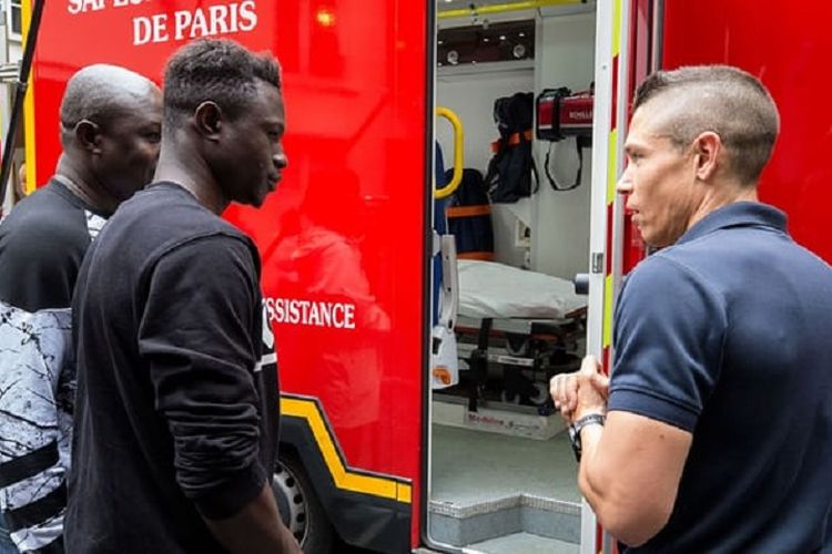 Mamoudou Gassama (tengah) ketika mengunjungi markas pemadam kebakaran di Paris, Perancis, Selasa (29/5/2018). Gassama menuai pujian setelah memanjat gedung demi menyelamatkan bocah empat tahun.