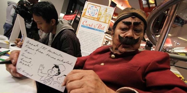 Suryadi atau akrab disapa Pak Raden di masa hidup saat menulis sebuah kartu pos yang akan ditujukan kepada Presiden Susilo Bambang Yudhoyono, di pusat perbelanjaan kawasan Senayan, Jakarta, Sabtu (21/4/2012). 
