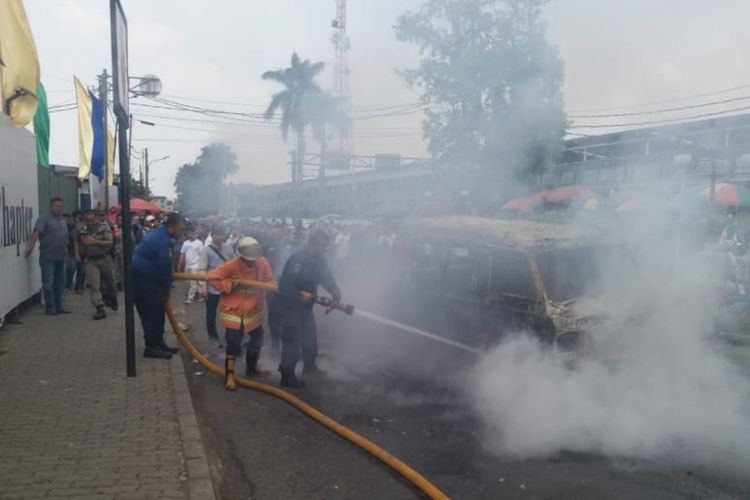 Petugas sedang memadamkan api yang membakar sebuah angkot di depan Halte Stasiun Bogor, Selasa (4/12/2019).