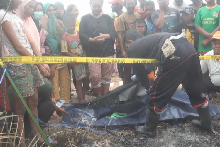 Petugas memasukkan sosok mayat yang hangus terbakar yang ditemukan warga saat menggembalakan kambingya ke dalam kantung mayat
