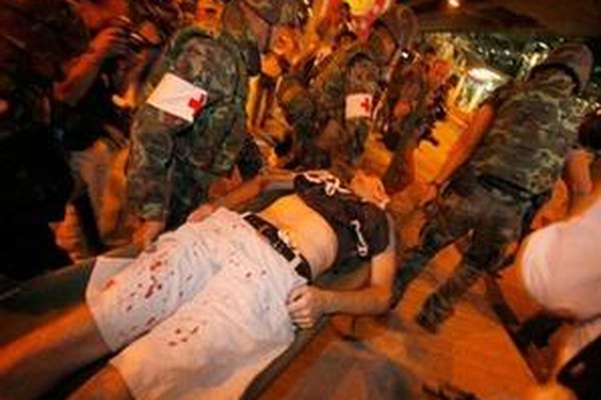 Thai soldiers carry an injured foreigner after small explosions have occurred near the site of anti-government protests Thursday, April 22, 2010, in Bangkok, Thailand. A series of small explosions went off Thursday near the massive encampment of anti-government protesters in Bangkok, wounding at least four people. An Associated Press reporter saw two injured people taken away for treatment after the first three blasts Thursday night. After a later fourth blast, AP reporters saw two seriously injured people lying motionless.