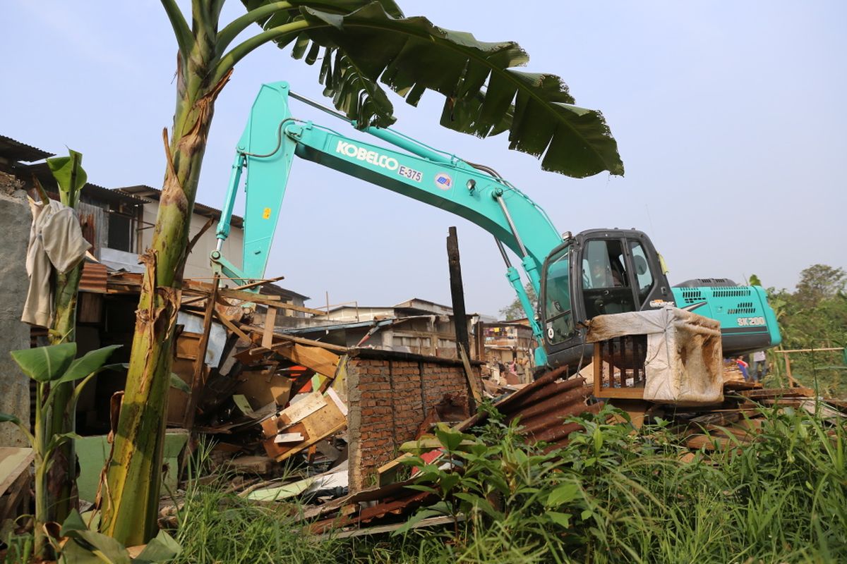 Petugas Satpol PP melalui dua back hoe membongkar bangunan semi permanen yang berada di area bantaran aliran Sungai Ciliwung di RW 01 Bukit Duri, Jakarta Selatan, Selasa (11/7/2017). Setelah bangunan diratakan dengan tanah, Balai Besar Sungai Ciliwung Cisadane (BBWSCC) akan memulai memasang sheet pile sebagai lanjutan proyek normalisasi Ciliwung.