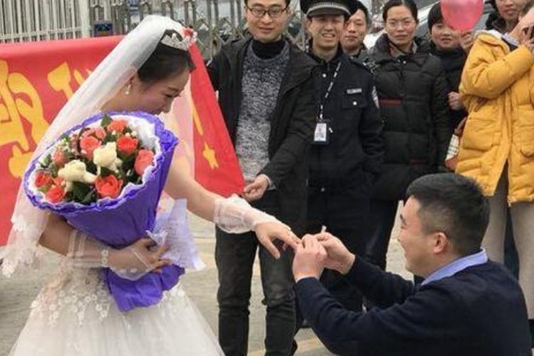 Zhao Wanping bersimpuh dan memakaikan cincin ke jari kekasihnya, Yuan Mingyu setelah dilamar di depan penjara tempat dia bekerja di Dazhou.
